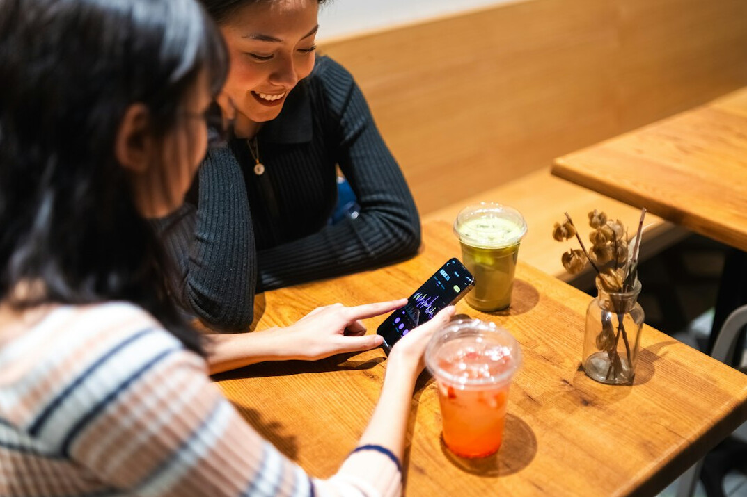 people scrolling on phones in cafe